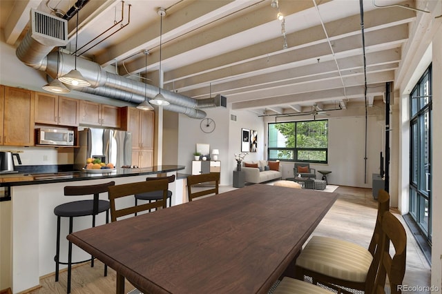 dining room with light wood-style floors, beamed ceiling, and visible vents