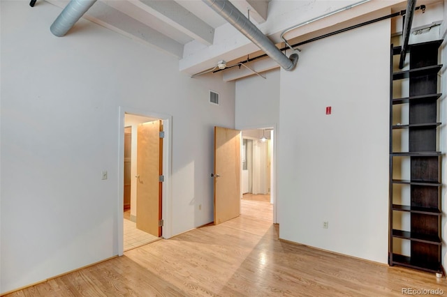 interior space featuring visible vents, a high ceiling, wood finished floors, and beamed ceiling
