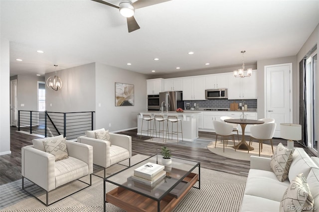 living room featuring hardwood / wood-style flooring, ceiling fan with notable chandelier, and sink