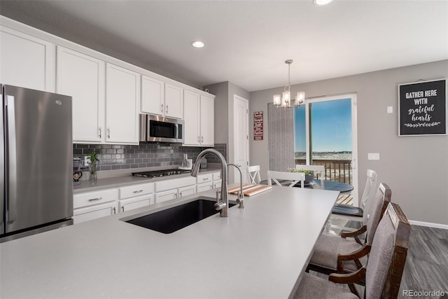 kitchen with hanging light fixtures, sink, appliances with stainless steel finishes, dark hardwood / wood-style flooring, and white cabinetry