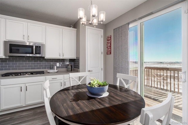 kitchen featuring appliances with stainless steel finishes, backsplash, decorative light fixtures, white cabinets, and a chandelier