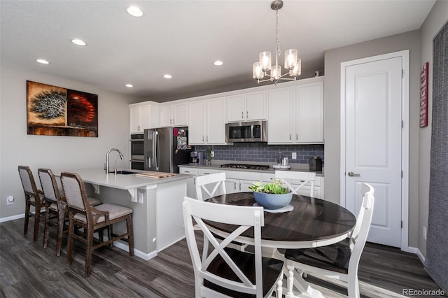 kitchen featuring hanging light fixtures, appliances with stainless steel finishes, tasteful backsplash, dark hardwood / wood-style flooring, and white cabinetry