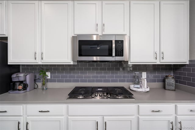 kitchen featuring stainless steel appliances, white cabinetry, and tasteful backsplash