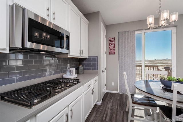 kitchen featuring an inviting chandelier, dark hardwood / wood-style floors, appliances with stainless steel finishes, tasteful backsplash, and white cabinetry