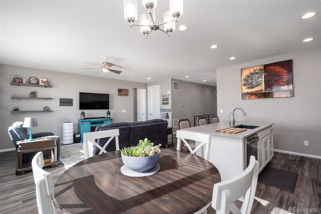 dining area with ceiling fan with notable chandelier, dark hardwood / wood-style flooring, and sink