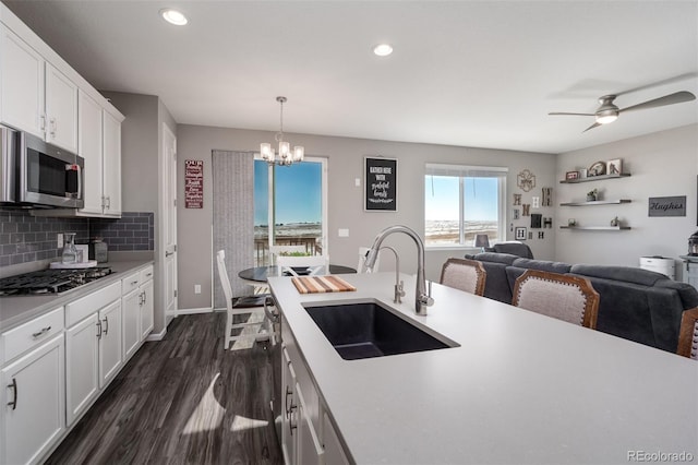 kitchen with sink, stainless steel appliances, dark hardwood / wood-style floors, decorative light fixtures, and white cabinets