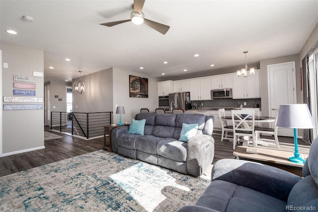 living room featuring ceiling fan with notable chandelier and dark hardwood / wood-style flooring