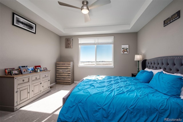 carpeted bedroom featuring a raised ceiling and ceiling fan