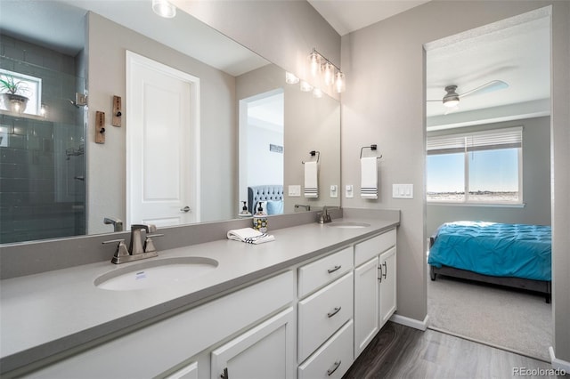 bathroom with hardwood / wood-style floors, vanity, a tile shower, and ceiling fan