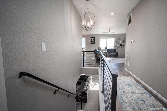 stairs featuring wood-type flooring and ceiling fan with notable chandelier