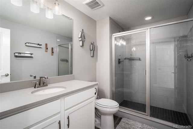 bathroom featuring vanity, toilet, an enclosed shower, and a textured ceiling