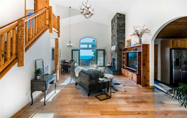 13416 Kuehster Rd, Littleton, CO 80127 - living area featuring a chandelier, arched walkways, light wood-style flooring, high vaulted ceiling, and stairs