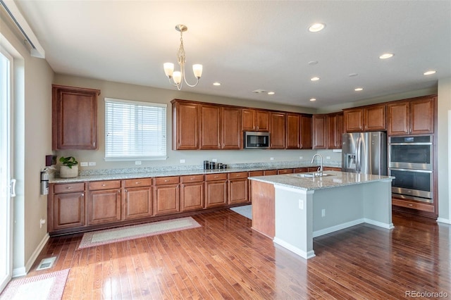 6265 S Ider Way, Aurora, CO 80016 - kitchen with stainless steel appliances, a sink, brown cabinets, a chandelier, and dark wood-style flooring