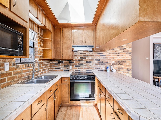 kitchen featuring sink, tile counters, and black appliances