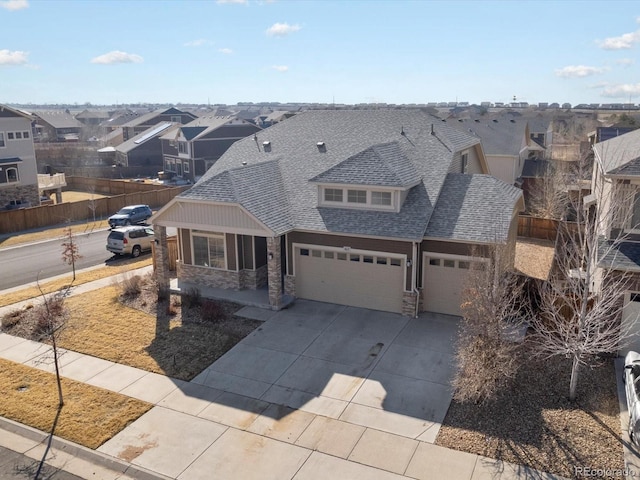 view of front of property featuring a garage, stone siding, a shingled roof, and a residential view