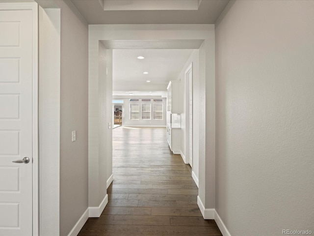 corridor with dark wood-type flooring, recessed lighting, and baseboards