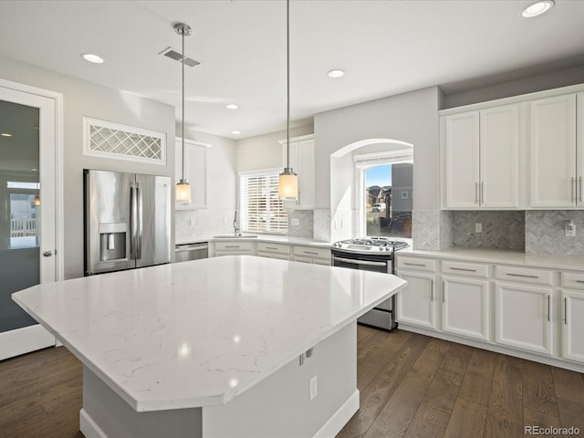 kitchen with arched walkways, white cabinets, dark wood finished floors, stainless steel appliances, and a sink