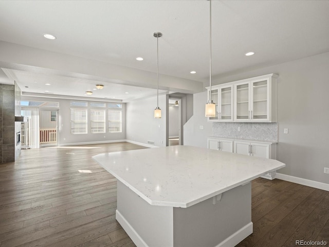 kitchen featuring light stone countertops, dark wood-style floors, tasteful backsplash, and white cabinets