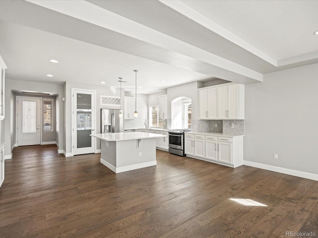 kitchen featuring white cabinetry, appliances with stainless steel finishes, dark wood-type flooring, and backsplash