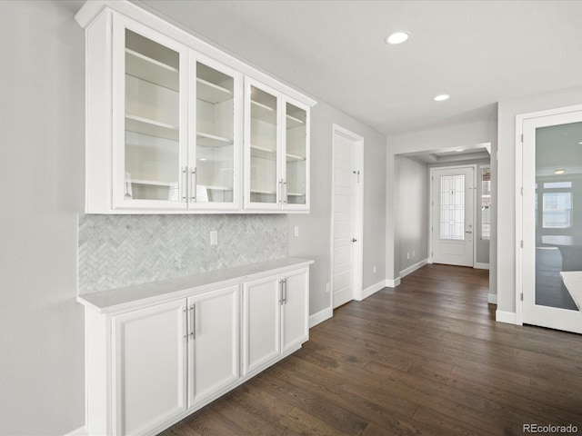 bar featuring baseboards, decorative backsplash, dark wood finished floors, and recessed lighting