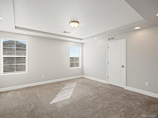 carpeted empty room featuring a tray ceiling, recessed lighting, visible vents, and baseboards