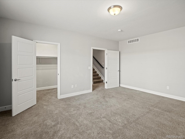 unfurnished bedroom featuring a closet, visible vents, a spacious closet, carpet flooring, and baseboards