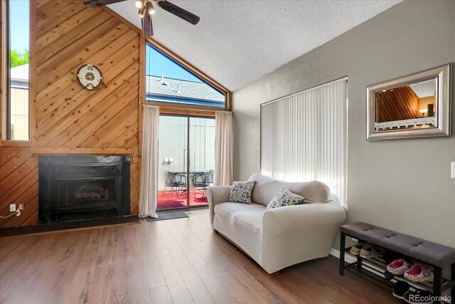 3853 S Genoa Ct Unit D, Aurora, CO 80013 - living area with a textured wall, ceiling fan, wood walls, a fireplace, and high vaulted ceiling