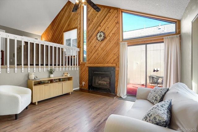 3853 S Genoa Ct Unit D, Aurora, CO 80013 - living area featuring ceiling fan, wood finished floors, wooden walls, a fireplace with raised hearth, and high vaulted ceiling