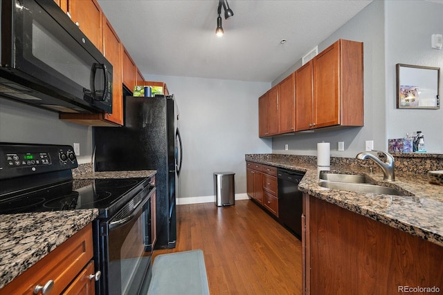 kitchen featuring dark stone countertops, sink, wood-type flooring, and black appliances