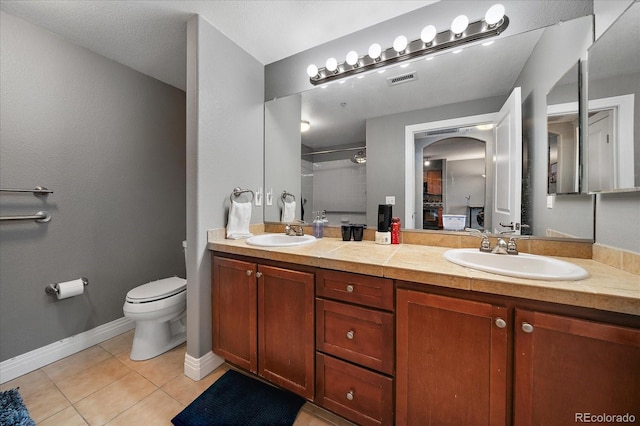 bathroom featuring tile patterned flooring, vanity, a shower, and toilet