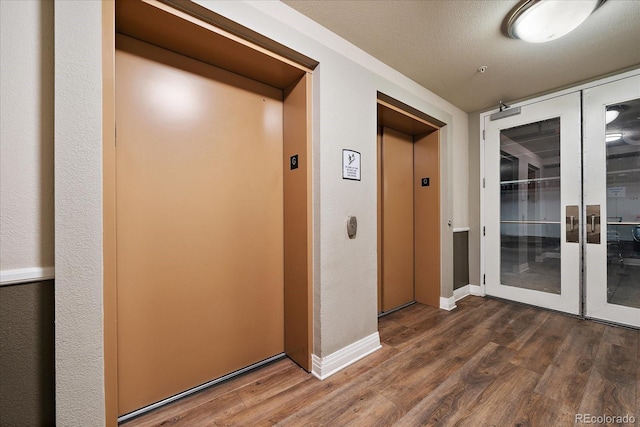 hall featuring dark wood-type flooring, elevator, and a textured ceiling