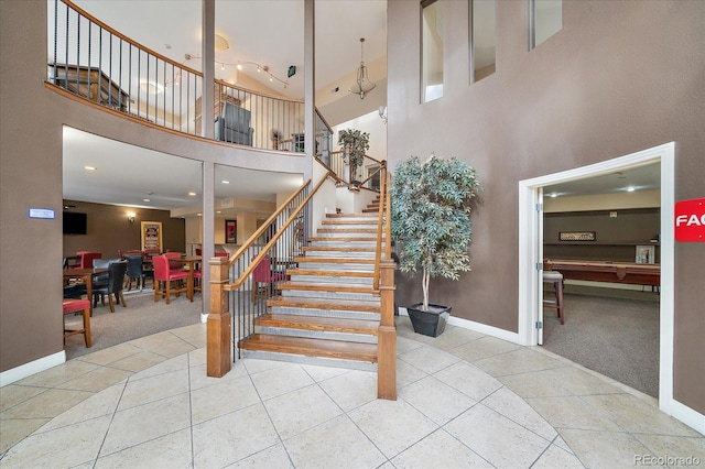 staircase with tile patterned flooring and a high ceiling