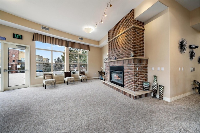 living room with track lighting, a fireplace, and carpet floors