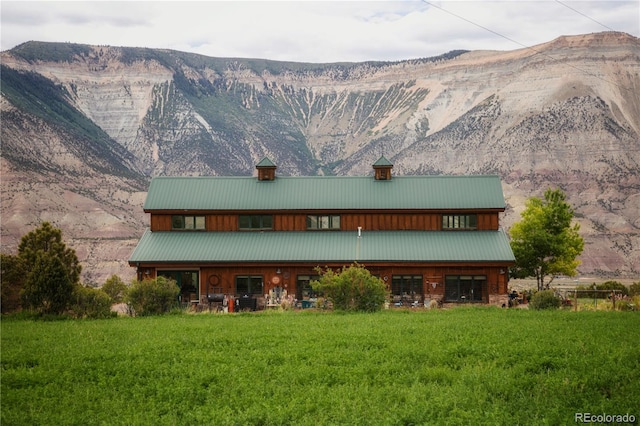 back of house featuring a mountain view and a lawn