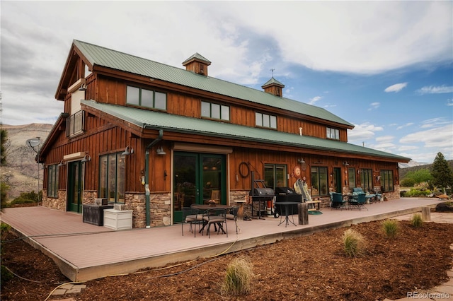 back of property featuring a patio and a wooden deck