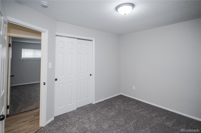 unfurnished bedroom featuring a closet, dark carpet, and a textured ceiling