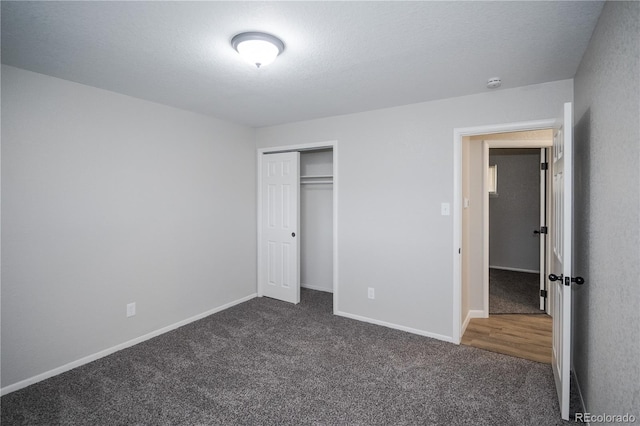 unfurnished bedroom with dark colored carpet, a textured ceiling, and a closet