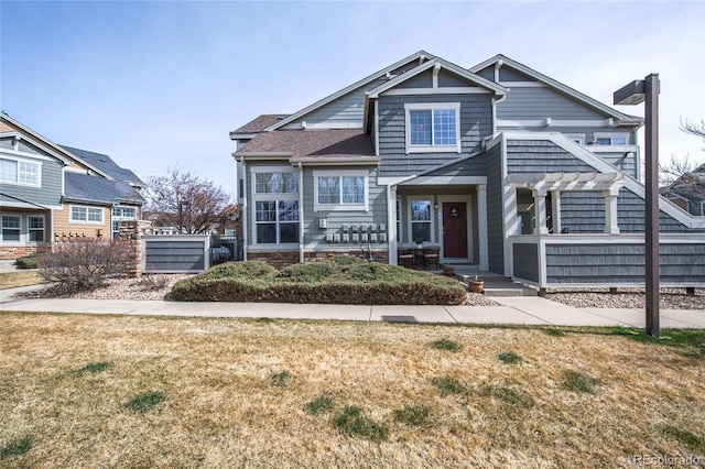 view of front of house featuring a shingled roof, fence, and a front lawn