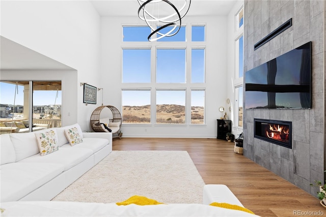 living area with a wealth of natural light, wood finished floors, a towering ceiling, and a tile fireplace