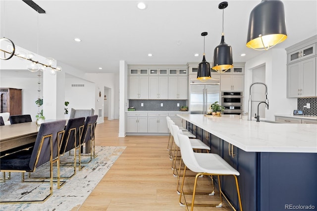 kitchen featuring light wood finished floors, backsplash, recessed lighting, and appliances with stainless steel finishes