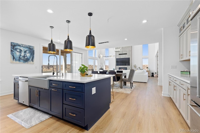 kitchen featuring a sink, light wood-style floors, an island with sink, and light countertops