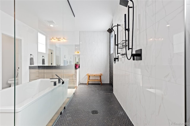 full bath featuring vanity, visible vents, walk in shower, tile walls, and toilet