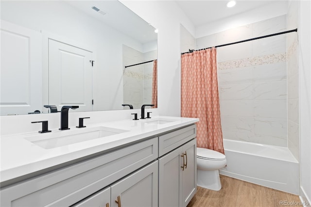 bathroom featuring a sink, toilet, wood finished floors, and double vanity