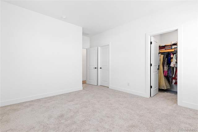 unfurnished bedroom featuring carpet, visible vents, baseboards, a closet, and a walk in closet