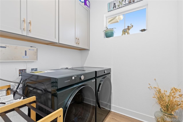 laundry area featuring light wood finished floors, cabinet space, baseboards, and separate washer and dryer