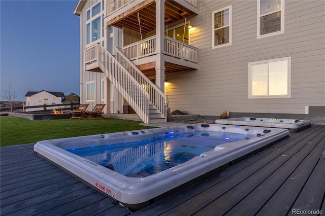 wooden deck with stairway, hot tub deck surround, and a yard