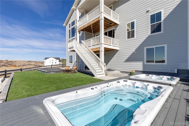 view of swimming pool featuring stairway, hot tub deck surround, and a lawn