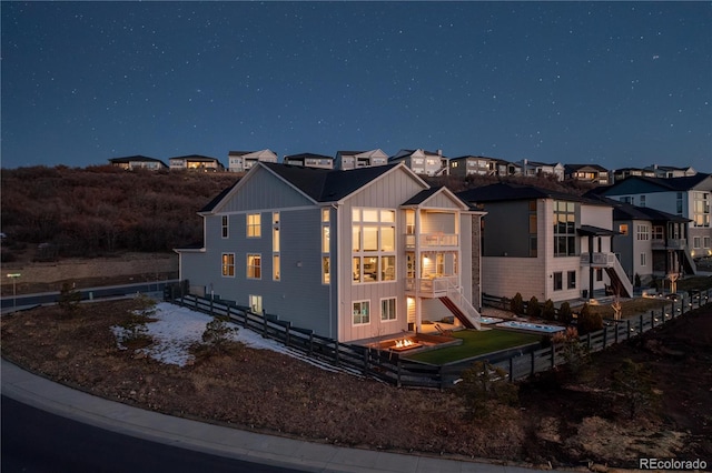 back of house at night with board and batten siding and fence