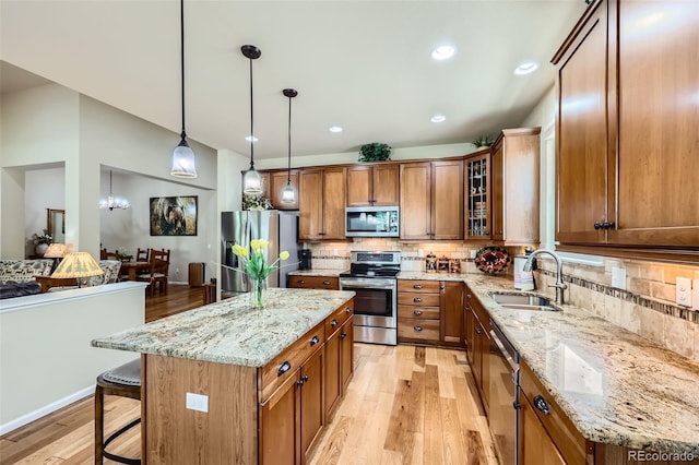 2872 Dreamcatcher Loop, Castle Rock, CO 80109 - kitchen featuring appliances with stainless steel finishes, brown cabinetry, light wood-style floors, a breakfast bar area, and decorative backsplash