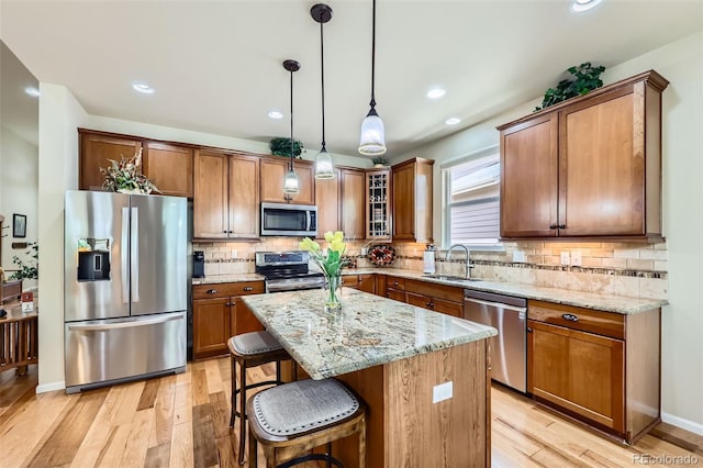 2872 Dreamcatcher Loop, Castle Rock, CO 80109 - kitchen with stainless steel appliances, light wood-style floors, light stone counters, brown cabinetry, and recessed lighting